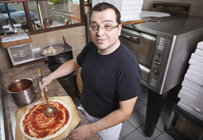 Pizzabagare fördelar tomatsås på pizza.