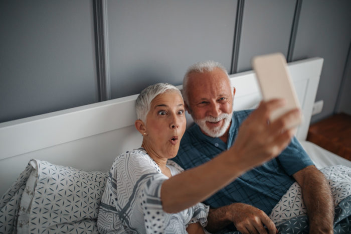 Äldre par tar en rolig selfie i sängen.